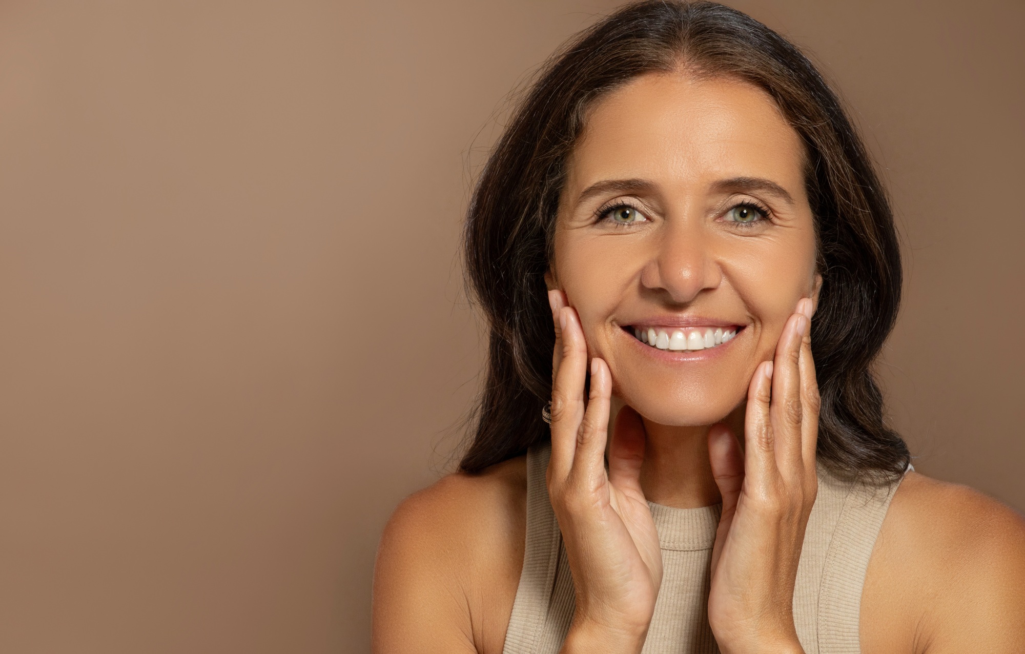 Happy caucasian elderly woman touching face with hands, enjoy anti-wrinkle treatment, natural beauty